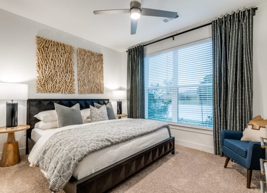 Aura 3Twenty Apartments bedroom with a large window and a bed and a ceiling fan
