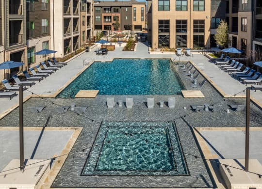 a swimming pool with lounge chairs and umbrellas in an apartment building