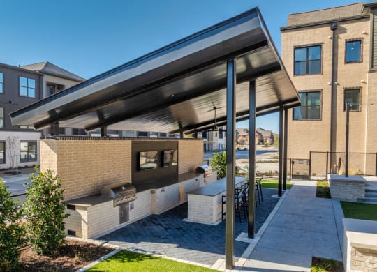 a patio with a grill and a shade canopy