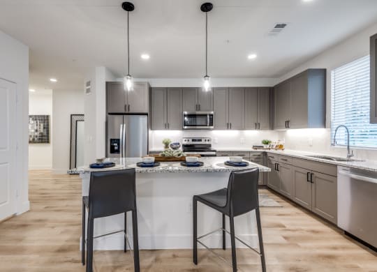 Aura 3Twenty Apartments  open kitchen with a large island with two stools