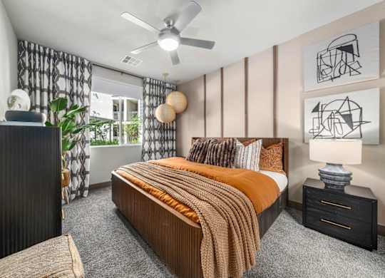 A bedroom with a bed, nightstand, and a ceiling fan.