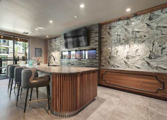 A bar area with a stone wall and wooden chairs.