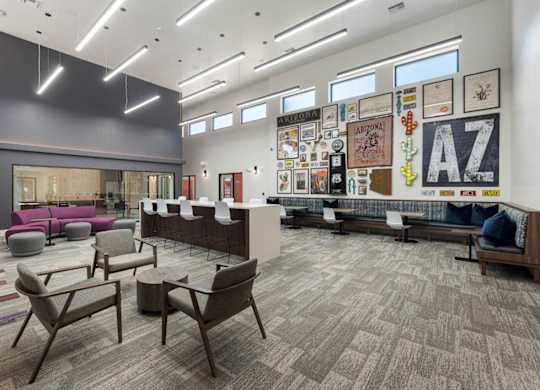 A large room with a carpeted floor and a long couch and chairs