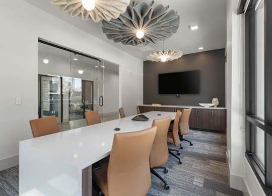 A conference room with a long white table and orange chairs.