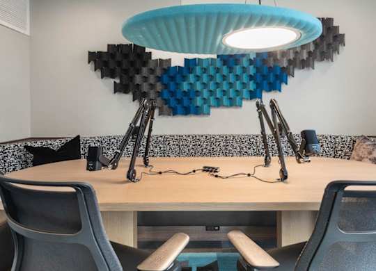 A modern office with a blue light hanging from the ceiling and a soundproofing panel on the wall.