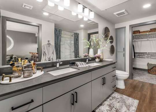 A bathroom with a large mirror, a sink, and a toilet.