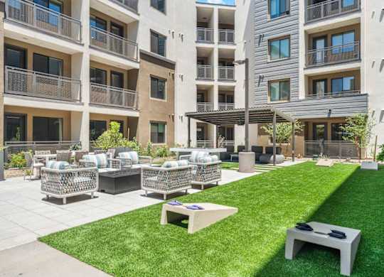 A grassy area with a bench and a table in front of apartment buildings.