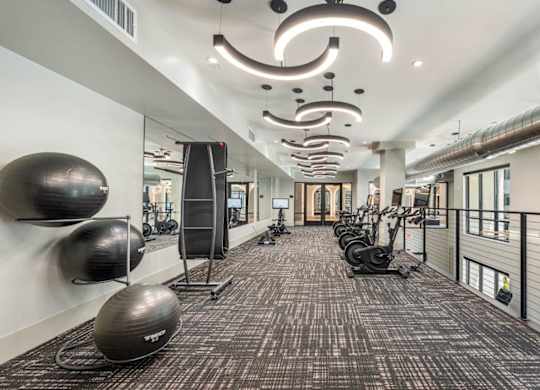 A gym with a variety of equipment including treadmills, weights, and exercise balls.