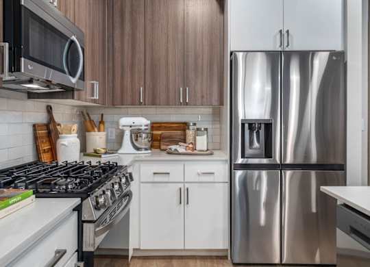 A modern kitchen with a stainless steel refrigerator and white appliances.