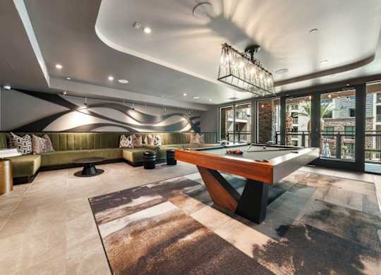 A room with a pool table and a green couch.