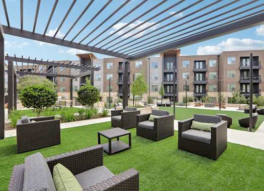 A patio with a black wicker sofa and chairs under a black metal roof.