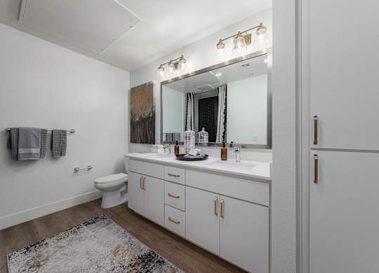 A bathroom with a white toilet, sink, and cabinets.