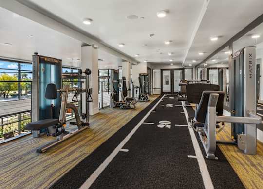 A gym with a variety of equipment including treadmills, weights, and exercise machines.