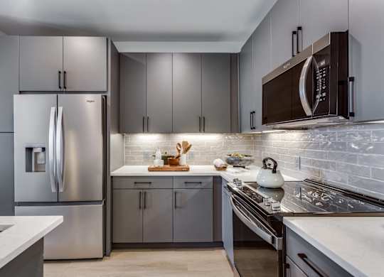 A modern kitchen with a stainless steel refrigerator and a white countertop.