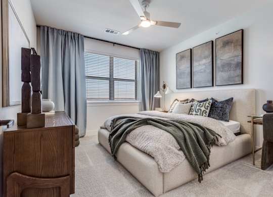 A bedroom with a bed, a dresser, and a ceiling fan.