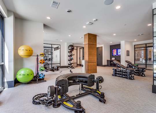 A gym with a variety of equipment including a rowing machine, exercise balls, and dumbbells.