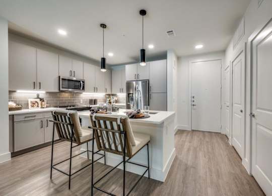 A kitchen with a white counter and brown chairs.