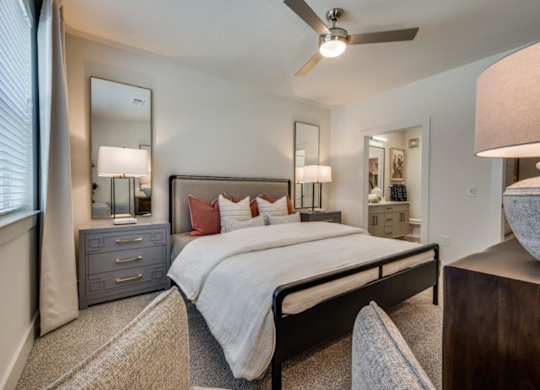 A bedroom with a large bed, a dresser, and a ceiling fan.