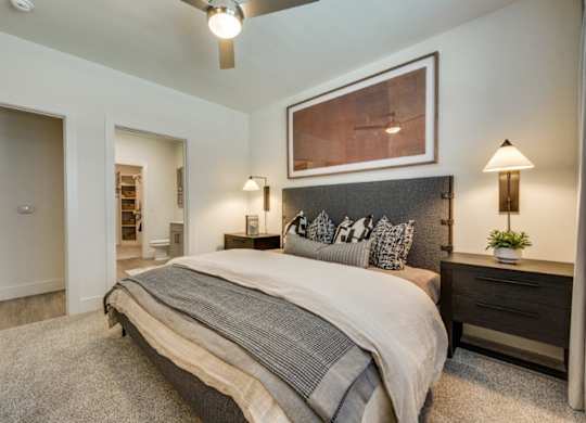 A bedroom with a large bed and a painting above it.
