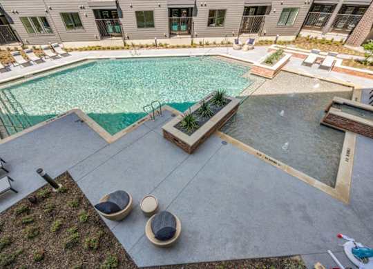 A pool surrounded by a concrete patio and a green lawn.