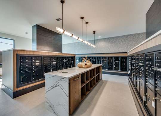 A modern kitchen with a marble island and dark cabinets.