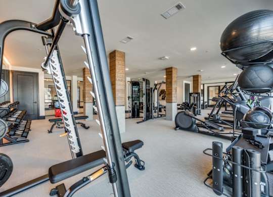 A gym with a variety of equipment including treadmills, weights, and exercise balls.