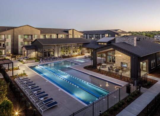 an aerial view of a swimming pool at night with apartments in the background