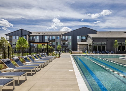 a swimming pool with lounge chairs in front of a building