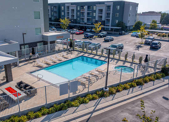 A pool surrounded by a fence and chairs.