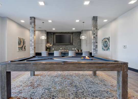 A pool table in a room with a stone pillar and a television mounted on the wall.