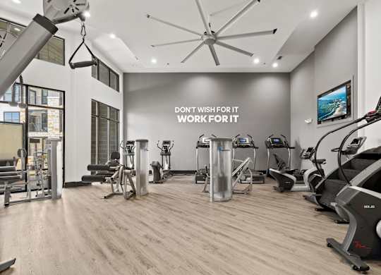 A gym with a variety of equipment and a motivational sign on the wall.