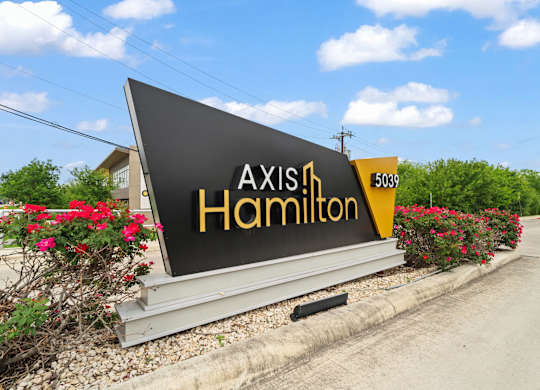 A sign for Axis in Hamilton is displayed in front of a building.