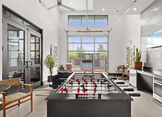 A foosball table is in the middle of a room with a chair and a plant.