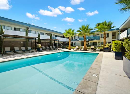 a swimming pool with palm trees and a building in the background