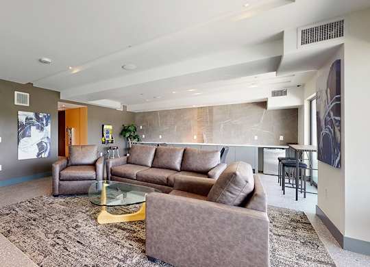 A living room with a brown couch and a glass coffee table.