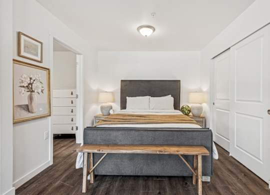 A bedroom with a bed, nightstands, and a bench.