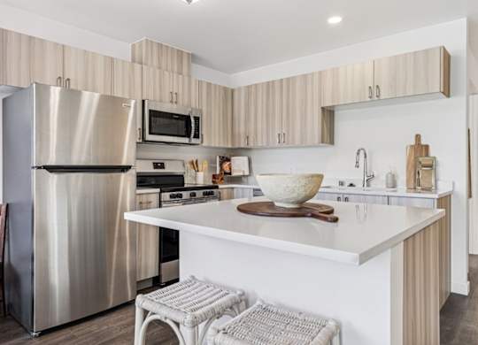 A modern kitchen with a stainless steel refrigerator and a white countertop.