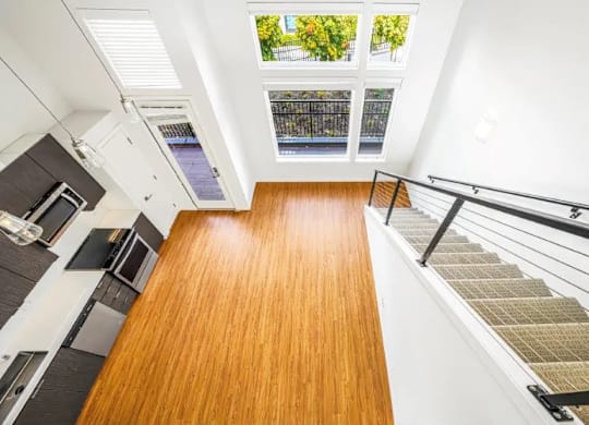 A wooden floor leads to a staircase with a metal railing.