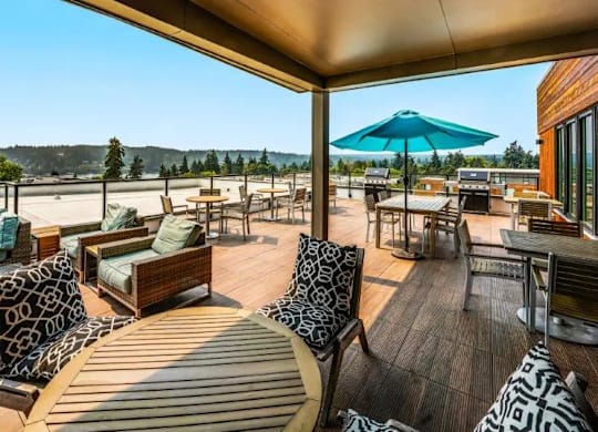 A wooden deck with a blue umbrella and patterned cushions.