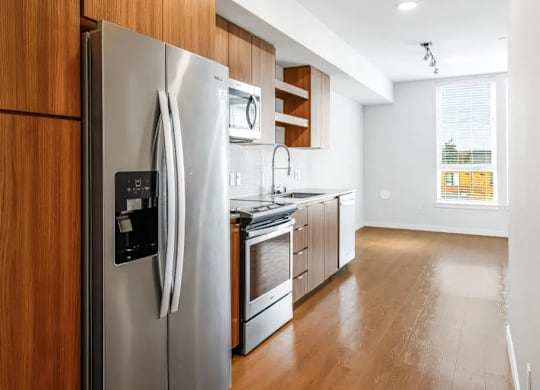 A modern kitchen with a stainless steel refrigerator and wooden cabinets.