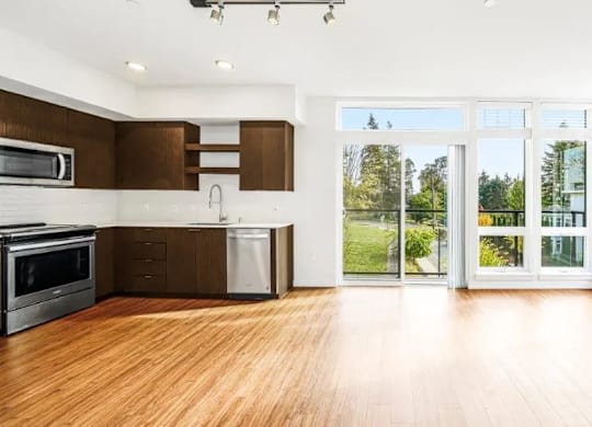 A modern kitchen with wooden floors and a large window.