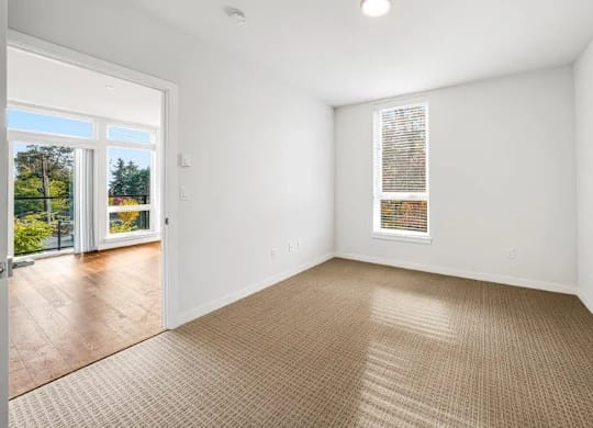 A room with a carpeted floor and a window with blinds.