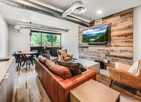A living room with a brown leather couch and a wooden wall.