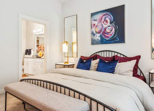 A bedroom with a large bed and a painting on the wall.