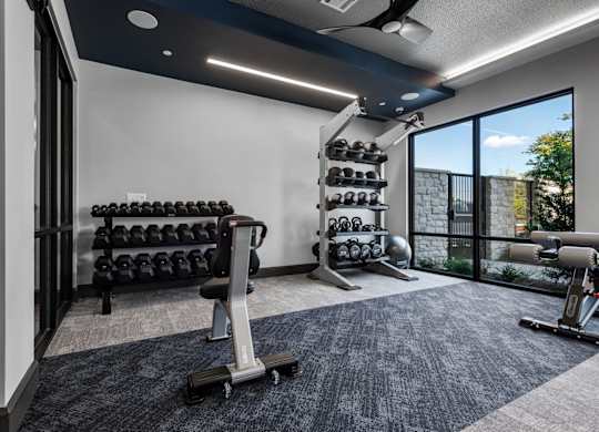 A spacious home gym with a variety of equipment including dumbbells, weight plates, and a bench.