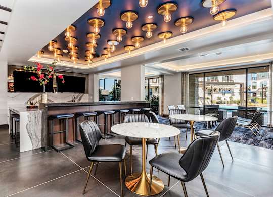 A modern bar with black chairs and a white counter.