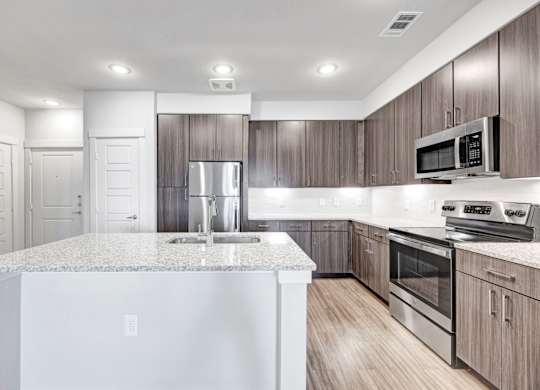 A modern kitchen with a granite countertop and stainless steel appliances.