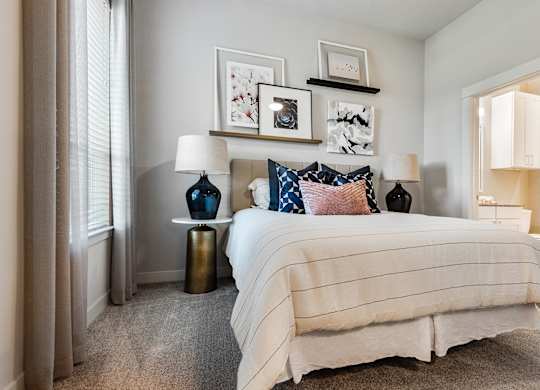 A bedroom with a bed, two lamps, and pictures on the wall.