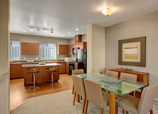 A modern kitchen with a glass dining table and chairs.