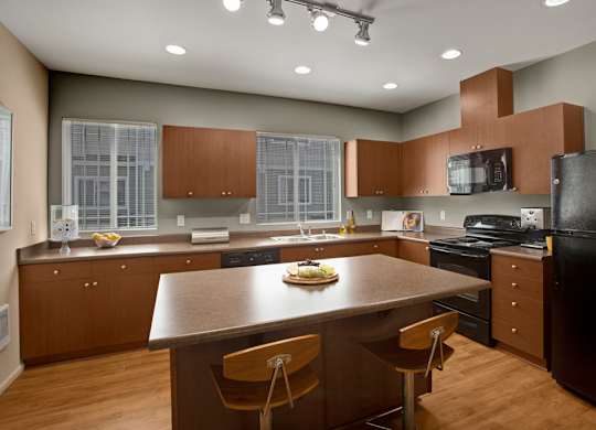 A modern kitchen with a black refrigerator and wooden cabinets.